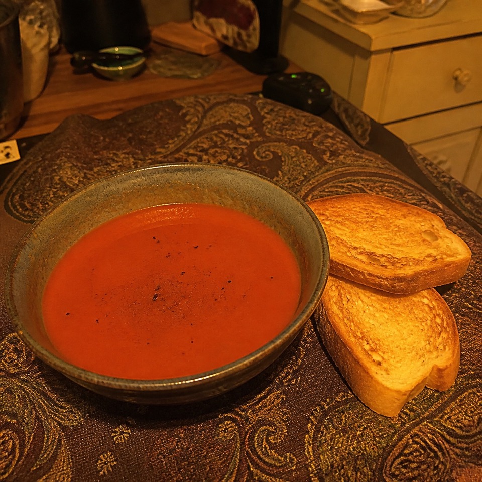 foto original de una sopa tomada con luz amarilla y un fondo desordenado